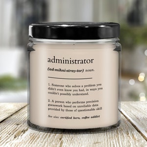 Puede incluir: Una vela blanca en un tarro de vidrio con tapa negra. La etiqueta dice "administrator (ad-mihni-stray-tor) sustantivo. 1. Alguien que resuelve un problema que ni siquiera sabías que tenías, de maneras que no podrías entender. 2. Una persona que realiza conjeturas precisas basadas en datos poco fiables proporcionados por personas con habilidades cuestionables Ver también: héroe certificado, adicto al café"