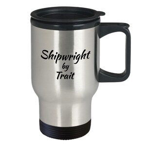 May include: Stainless steel travel mug with a black lid and handle. The mug has the text "Shipwright by Trait" printed on it.
