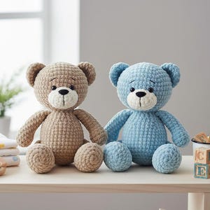 Può includere: Due orsacchiotti all'uncinetto fatti a mano, uno beige e uno azzurro, sono seduti fianco a fianco su una mensola di legno. Ogni orso ha un muso bianco e occhi neri. Sono visibili anche articoli per bambini.