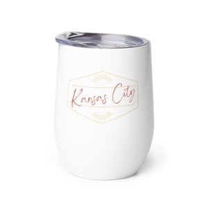 May include: White stainless steel tumbler with a gold and red logo that says "Kansas City" in a script font.