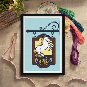 May include: A framed cross-stitch design of a pub sign with a white horse and the text "The Prancing Pony".
