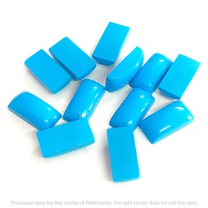 Puede incluir: Una colección de gemas rectangulares turquesas brillantes con bordes redondeados. Las gemas están dispersas sobre una superficie blanca, mostrando su textura pulida y suave. La imagen incluye el texto "Aayat DesignIN".