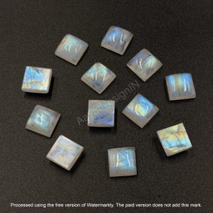 May include: A collection of eleven square-cut moonstone cabochons featuring a translucent white base with iridescent blue and gold flashes. Each gemstone displays a smooth, polished surface with a distinct adularescence effect.