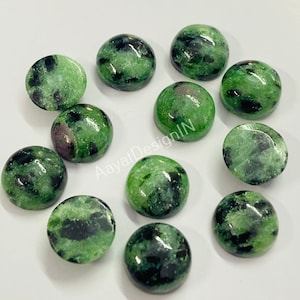 May include: Twelve round green and black gemstone cabochons. The cabochons are approximately 10mm in diameter and have a smooth, polished surface.