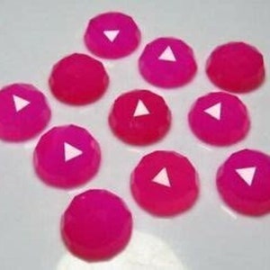 May include: Twelve pink cabochon gemstones with a white triangle design. The gemstones are approximately 10mm in diameter.