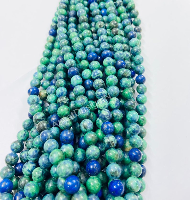 May include: A strand of green and blue gemstone beads. The beads are round and have a mottled appearance.