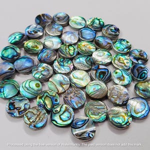 May include: A collection of round, iridescent abalone shell inlay pieces. The pieces are various shades of blue, green, and gold.