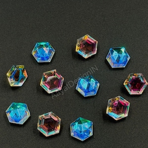May include: A collection of iridescent, hexagonal crystals. The crystals display a spectrum of colors, including blues, pinks, and yellows, with a faceted design. They are scattered on a dark surface, creating a sparkling effect.