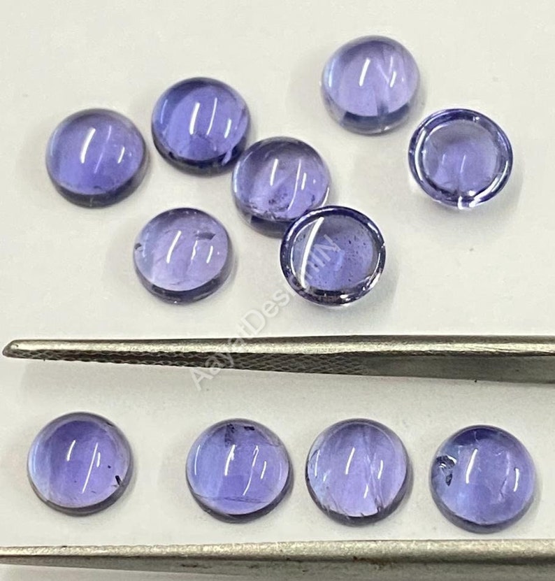May include: Ten round, purple amethyst cabochons, some with a slight shimmer, arranged in two rows on a white surface. The cabochons are approximately 10mm in diameter.