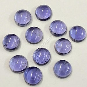 May include: Ten round, smooth, purple gemstones with a slight sheen. The gemstones are approximately 1 cm in diameter.