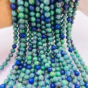 May include: A strand of green and blue gemstone beads. The beads are round and have a mottled appearance.