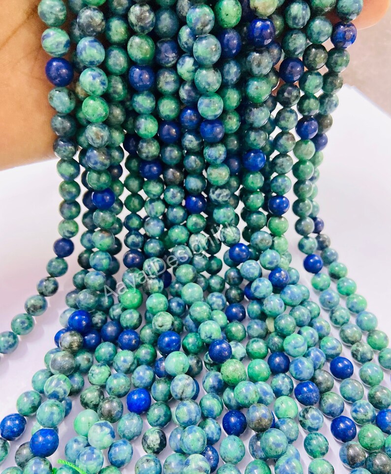 May include: A strand of green and blue gemstone beads. The beads are round and have a mottled appearance.