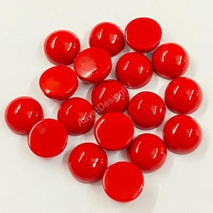 Op de afbeelding: Een verzameling van 15 ronde, rode cabochons. De cabochons zijn glad en glanzend en zijn in een willekeurig patroon gerangschikt.