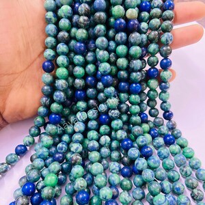 May include: A strand of green and blue gemstone beads. The beads are round and have a mottled appearance.