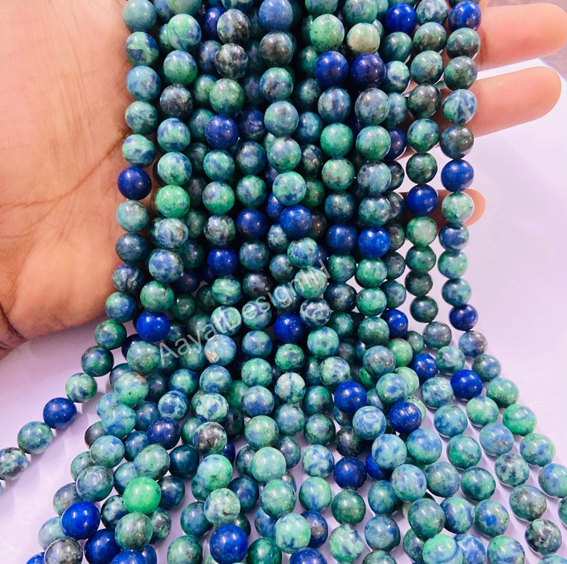 May include: A strand of green and blue gemstone beads. The beads are round and have a mottled appearance.