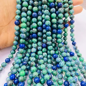 May include: A strand of green and blue gemstone beads. The beads are round and have a mottled appearance.