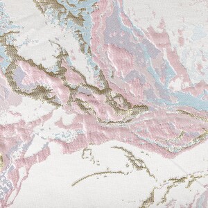 Puede incluir: Una tela tejida con un patr&oacute;n abstracto sobre una base blanca. El dise&ntilde;o incorpora hilos texturizados en tonos rosa suave, azul claro y oro met&aacute;lico, creando un efecto jaspeado en toda la superficie del material textil.