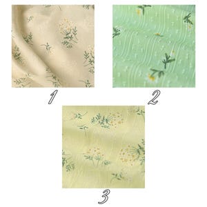 Op de afbeelding: Drie stofstalen met bloemmotieven. De eerste is cr&egrave;me met witte en groene bloemen. De tweede is lichtgroen met witte madeliefjes en verticale gestructureerde strepen. De derde is lichtgeel met witte en groene bloemtrossen op de stof.