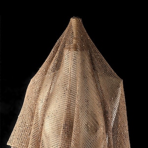 Puede incluir: Una tela marr&oacute;n, transparente, de red drapeada sobre una forma. La tela tiene una textura tejida y una apariencia ligeramente brillante.