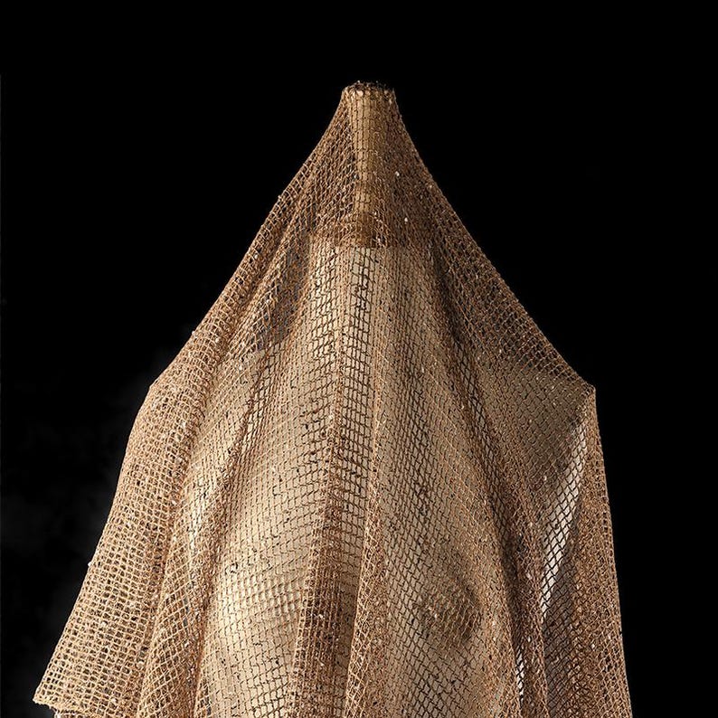 Puede incluir: Una tela marr&oacute;n, transparente, de red drapeada sobre una forma. La tela tiene una textura tejida y una apariencia ligeramente brillante.