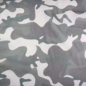 May include: A fabric featuring a camouflage pattern in shades of white, light gray, and dark gray. The design consists of irregular, organic shapes that overlap to create a classic military-inspired motif across the entire surface of the material.