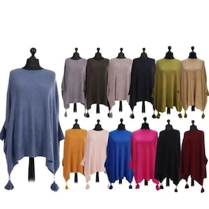 May include: A collection of 12 knitted ponchos with tassels in various colours, including blue, green, brown, pink, red, and yellow.