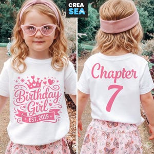 May include: A white ceramic mug with a black handle and the text "But First, Coffee" in a bold, black font. The mug is set against a blurred background, suggesting a cozy setting.