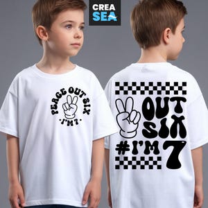 Könnte beinhalten: Weißes T-Shirt mit schwarzer Grafik auf Vorder- und Rückseite. Die Grafik auf der Vorderseite zeigt "Peace Out Six" mit einem Peace-Zeichen und "I'm 7". Auf der Rückseite steht "Out Six" mit einem Peace-Zeichen und "# I'm 7".