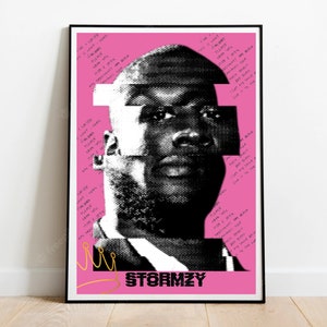 May include: A framed poster featuring a black and white portrait of Stormzy on a pink background. The image is stylized with geometric shapes and handwritten text. The word "STORMZY" is printed at the bottom.