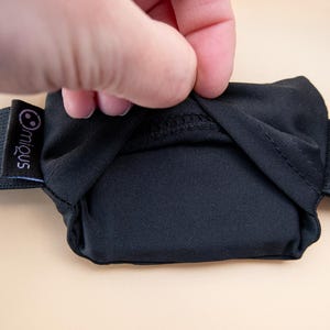 May include: Black eye mask with an elastic band. The mask is made of a soft, opaque material. The brand name "miqous" is printed on a small black tag attached to the elastic band.