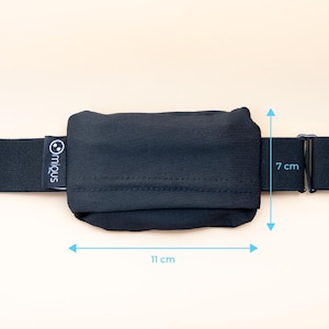 May include: A black pouch, 11 cm long and 7 cm high, attached to a black elastic strap. The pouch has a stitched seam across the middle. The brand name "miqus" is printed on the strap. The background is a solid, light beige color.