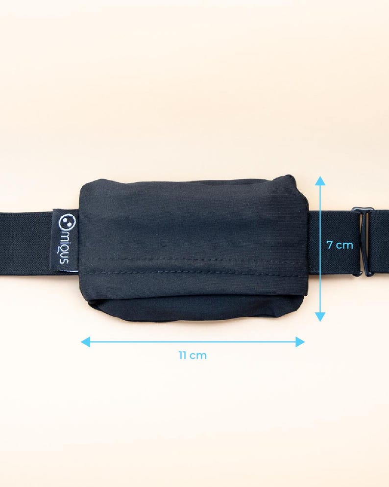May include: A black pouch, 11 cm long and 7 cm high, attached to a black elastic strap. The pouch has a stitched seam across the middle. The brand name "miqus" is printed on the strap. The background is a solid, light beige color.