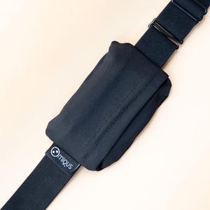 May include: Black adjustable strap with a small pouch. The strap has a metal buckle and a small tag with the brand name "@migus". The pouch is made of a soft, dark fabric.