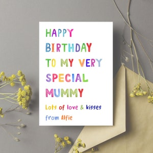 May include: A white birthday card with colorful text that reads "HAPPY BIRTHDAY TO MY VERY SPECIAL MUMMY." The card includes the message "Lots of love & kisses from Alfie." The card is next to a brown envelope and yellow flowers.