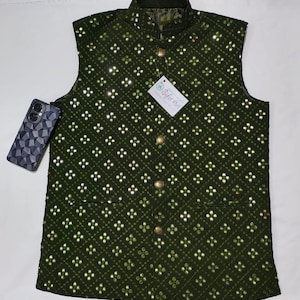 Op de afbeelding: Een donkergroen, mouwloos vest met een ruitpatroon en zilveren pailletten. Het vest heeft een mandarijnskraag en vijf gouden knopen aan de voorkant. Het vest heeft een klein zakje aan de linkerkant. Het label op het vest zegt "Sita Art".