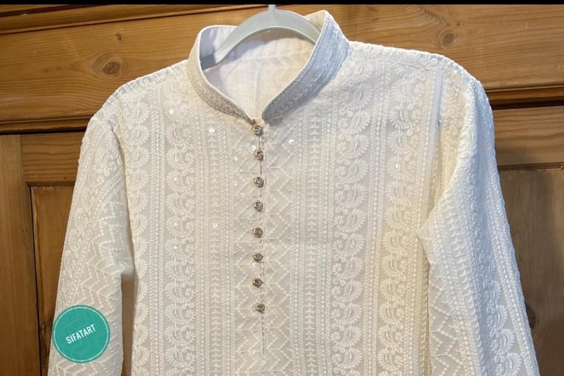 May include: White embroidered kurta with a button-up closure and long sleeves. The kurta is made of a delicate fabric and features intricate floral patterns.