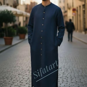 Könnte beinhalten: Eine lange, marineblaue Tunika mit Stehkragen und Holzknöpfen. Die Tunika hat lange Ärmel und Taschen. Der Text "Sifatart" ist unten sichtbar. Die Person trägt weiße Turnschuhe.