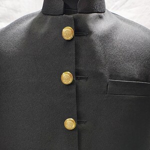 Puede incluir: Un chaleco negro con cuello mandar&iacute;n y cuatro botones dorados. El chaleco tiene un bolsillo en el lado derecho.