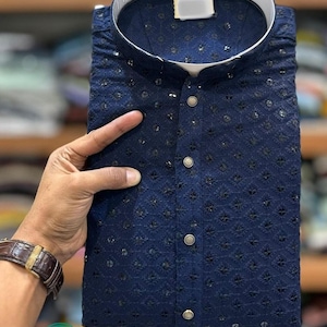 K&ouml;nnte beinhalten: Eine marineblaue Kurta mit wei&szlig;em Kragen und aufwendigen Stickereien. Die Kurta hat einen Knopfverschluss und ein traditionelles Design.