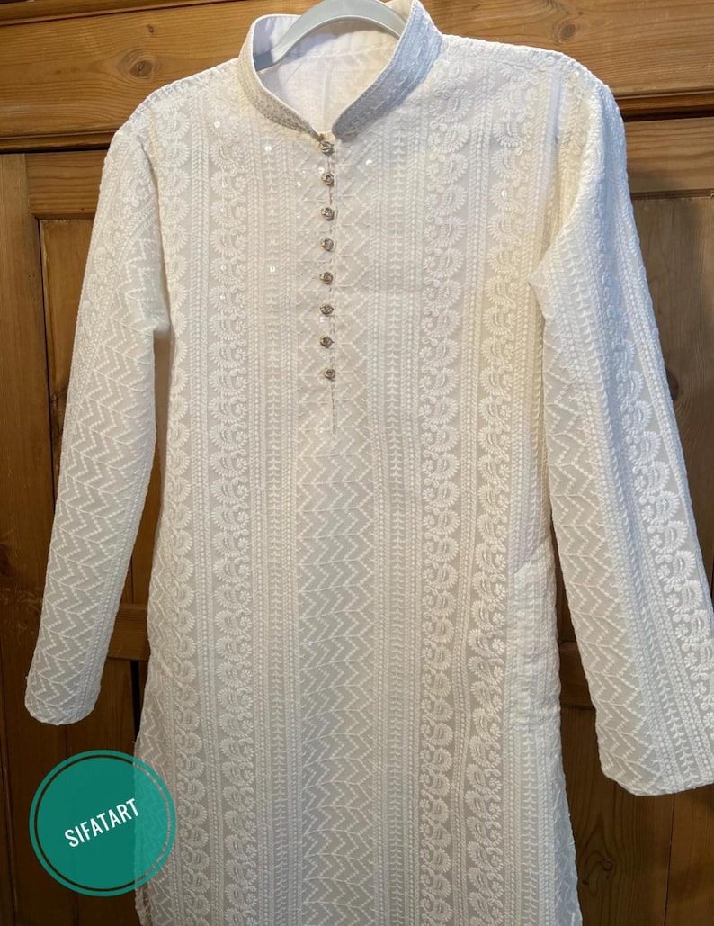 May include: White long-sleeved kurta with intricate embroidery and a button-up closure at the neckline.