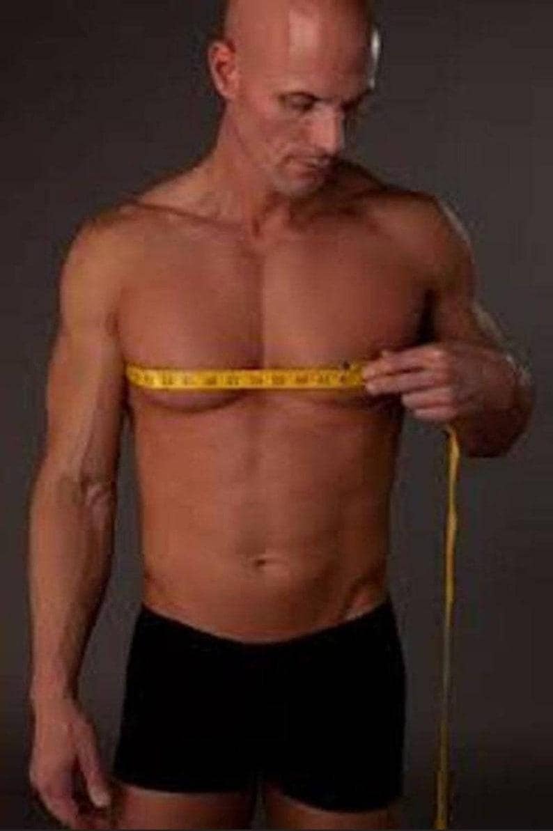May include: A man is measuring his chest with a yellow tape measure. He is wearing black underwear.