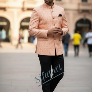 Puede incluir: Chaqueta melocotón estampada con cuello mandarín y botones dorados, combinada con pantalón negro y zapatos marrones. La chaqueta tiene un diseño geométrico sutil. El texto "Sifatart" es visible en la parte inferior de la imagen.