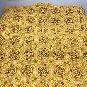 Könnte beinhalten: Eine gehäkelte Tagesdecke mit einem geometrischen Muster in Gelb-, Orange- und Brauntönen.