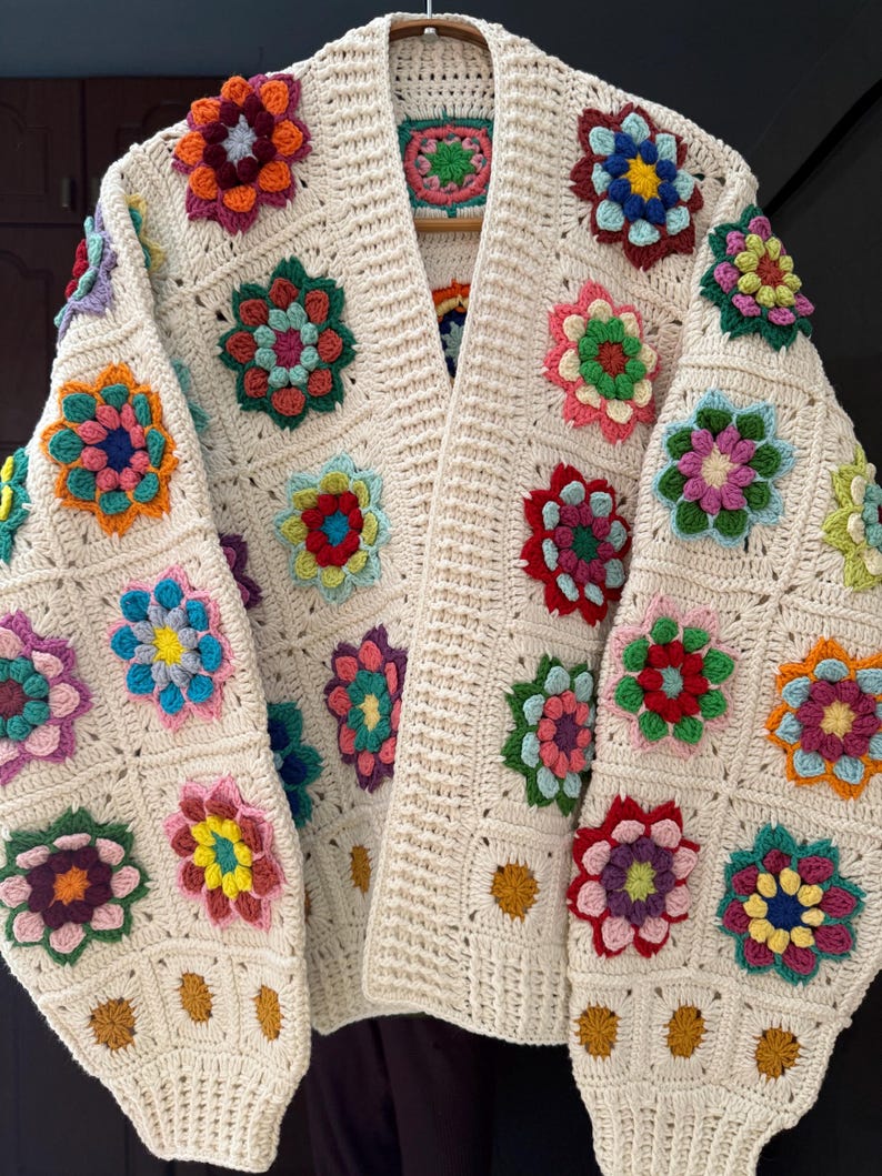 Puede incluir: C&aacute;rdigan de crochet color crema, abierto por delante, adornado con aplicaciones florales coloridas. Las flores presentan tonos de rojo, rosa, amarillo, azul y verde. El c&aacute;rdigan est&aacute; hecho de un hilo suave y texturizado y tiene un corte holgado.