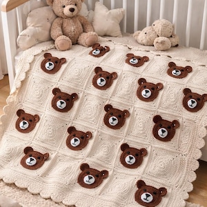 May include: A cream-colored crochet baby blanket with a repeating pattern of brown bear faces. The blanket is placed on a white crib with a teddy bear and other stuffed animals. The blanket has a scalloped edge.
