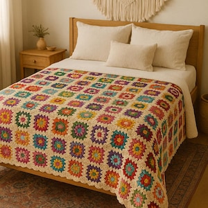 Può includere: Una colorata coperta all'uncinetto fatta a mano con un motivo floreale, drappeggiata su un letto di legno. La coperta presenta quadrati di vari colori, tra cui rosso, giallo, blu e verde. Il letto è fatto con cuscini e lenzuola bianche.
