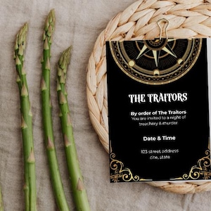 May include: A black invitation card with gold accents and the text "THE TRAITORS" is held by a gold clip. The card includes the text "By order of The Traitors You are invited to a night of treachery & murder". Green asparagus spears are on the left.