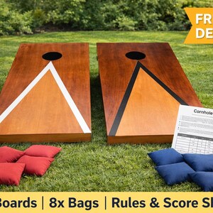 May include: Two wooden cornhole boards with a brown finish, each with a black hole and a white or black triangle design. Includes red and blue bean bags, and a score sheet. The image text reads "2 Boards | 8x Bags | Rules & Score Sheet".