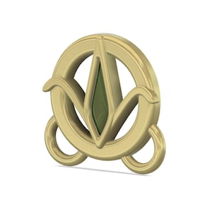 May include: A gold-colored metal charm with a stylized green leaf design. The charm has a circular shape with a smaller circle on each side.