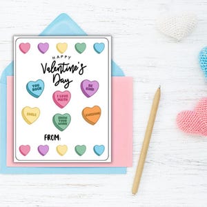 May include: A printable Valentine's Day card with a pink, blue, and white color scheme. The card features a design of candy hearts with messages like "You Rock", "I Love Math", and "Be Kind". The card also includes the text "Happy Valentine's Day" and "From:".
